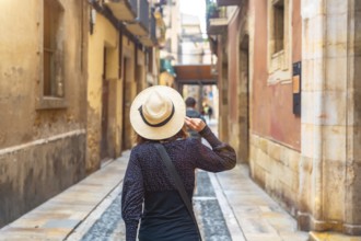 Tourist with straw hat walking in the medieval city of tarragona, spain, enjoying the historical