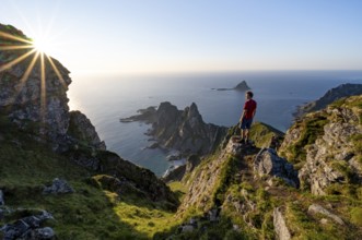 Mountaineer on the summit of Måtind or Måtinden, view of picturesque coastal landscape with sun
