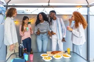 Multi-ethnic group of friends talking while celebrating party in the afternoon at rooftop