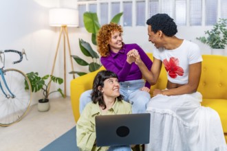Transgender person and lesbian couple having fun using laptop together at home