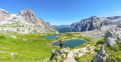 Tourist enjoying the scenic view of tre cime di lavaredo and alpine lakes on a sunny summer day in