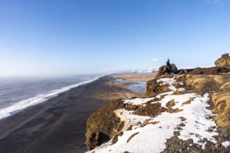 Young woman on the viewing platform on top of Mount Dyrholaey at winter sunset in Iceland