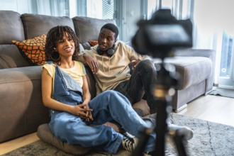 Two influencers are recording a vlog in their living room, discussing lifestyle and fashion tips