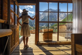 Woman enjoying breathtaking views of lake braies and surrounding mountains from a traditional