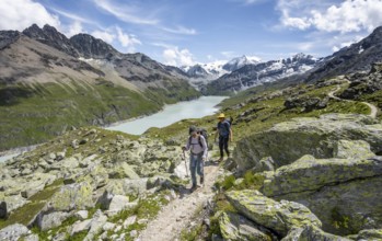 Two mountaineers on a hiking trail, view of a blue mountain lake, Lac des Dix reservoir, mountain