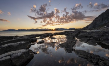 Clouds reflected in a small pond on a rocky coast, coastal landscape at sunset, Henningsvær,