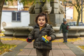 Little boy smiling and playing running through a city park