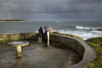 Tourists looking at sea in bad weather from the Pointe de Combrit near Bénodet, Finistère,