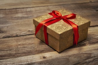 Gift present birthday Christmas concept, gift box with red ribbon on wooden background
