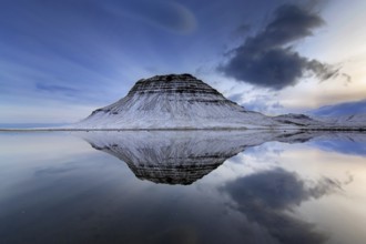 Kirkjufell, nunatak hill covered in snow reflected in water of fjord on the Snæfellsnes peninsula