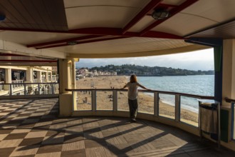 A young woman looking at the beautiful Grande Plage in Saint Jean de Luz at sunset, vacation in the