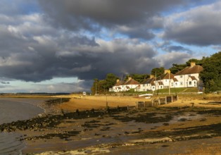 Storm clouds over beach and buildings at Bawdsey Quay, Suffolk, England, UK