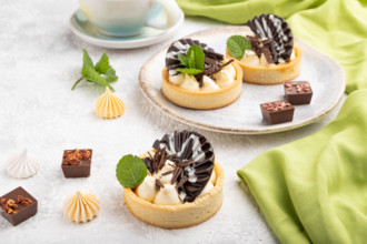 Sweet tartlets with chocolate and cheese cream with cup of coffee on a gray concrete background and