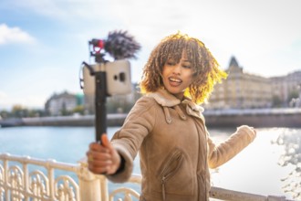 Beauty latin young female content creator vlogging online in the city next to the river