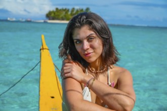 Young woman relaxing on traditional outrigger boat, enjoying the turquoise waters of daku island in
