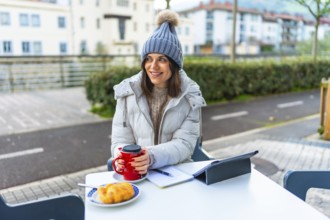 Beauty woman wearing warm clothes and woolly hat warming hands with hot coffee in a sidewalk