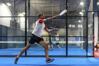 Full length photo of a mature sportive man trying to reach the ball while playing paddle tennis in