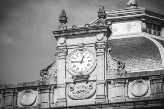 Black and white image of an ornate clock tower atop a historic building, showcasing intricate