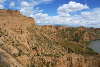 Ein felsiger Canyon mit einem klaren blauen Himmel und weißen Wolken darüber, Barrancas de Burujón,