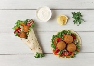 Tortillas, wrapped falafel balls, with fresh vegetables, vegetarian healthy food, on a wooden white