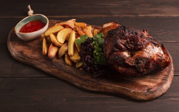 Pork knuckle, in soy-honey sauce, with fried potatoes, on a wooden chopping board, homemade, no