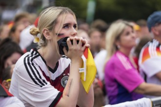 A woman watches the football match in the fan zone at the Brandenburg Tor during the quarter-final