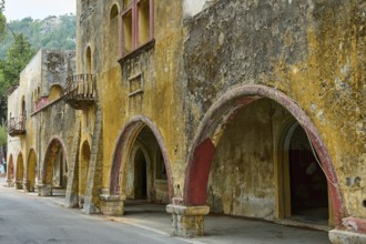 Street with dilapidated yellow historic-style buildings characterised by arches, balconies and