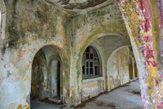Abandoned rooms with dilapidated walls and arches, overgrown and in a state of decay, Italian