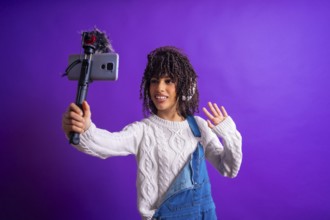Young latin american content creator waving and recording video with smartphone and external