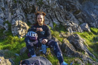 Young climber woman resting on a mountain after her climbing activity, checking her smartwatch