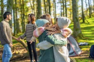 Three young caucasian children embracing enjoying camping day in the forest with family