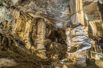 Tourists admiring the stalactites and stalagmites inside the famous postojna cave, a popular