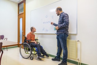 Man with cerebral palsy and colleague using board during brainstorming in a modern coworking