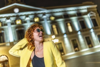 Confident woman with casual yellow clothes and sunglasses enjoying night in the city alone