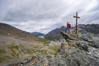 Mountaineer on rock with summit cross, summit behind the Labane des Dix, Valais Alps, Valais,