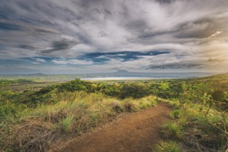 Landscape of a dirt road overlooking Masaya Lagoon. Nature trail overlooking a distant volcano