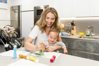 Happy mother and baby boy enjoying creative time together, painting with colorful markers in a