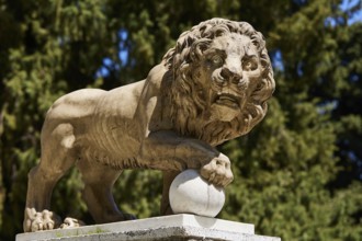A stone lion statue holding a ball with a forest in the background, Rodini Park, Municipal Park,