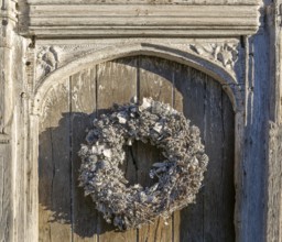 Silver white Christmas wreath on ancient old door in Lavenham, Suffolk, England, UK