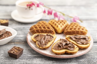 Homemade waffle with chocolate butter and cup of coffee on a gray wooden background. side view,