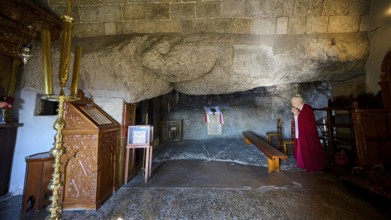 Praying woman in a sacred space with rock walls and an altar, rock grotto, Monastery tis