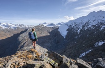 Mountaineer standing on a rock, surrounded by an impressive mountain landscape with snow-covered