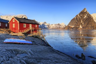 Red wooden house at fjord in front of Bergen, morning light, reflection, winter, Reine,
