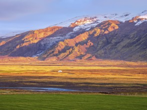 View over meadows to glacier Eyjafjallajökull, Fljotsdalur valley, warm light at sunset, Iceland,