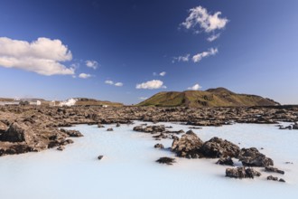 Outdoor thermal pool and geothermal power plant in front of volcanic mountains, Blue Lagoon,