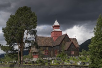 Old church and tree-covered cemetery under a dramatic sky, Dovre church, Dovre kyrkje, Dovre, Fylke