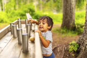 Young child exploring and interacting with a sensory play station in a natural park setting,