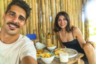 Tourists having breakfast with mango and scrambled eggs in a bamboo hut during their holidays in