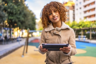 Frontal portrait of a beauty and happy latin woman holding digital tablet working outdoors