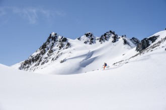 Ski tourer on the descent, minimalist winter landscape, white snow and dark mountains on the